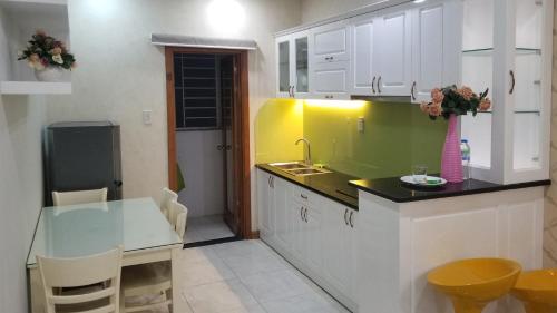 a kitchen with white cabinets and a sink and a table at CH Mường Thanh Luxury 60 Trần Phú. Nha Trang in Nha Trang