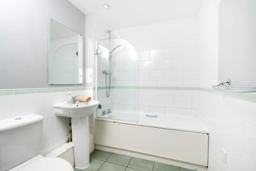 a white bathroom with a sink and a shower at Cosy Flat right opp tube station in London