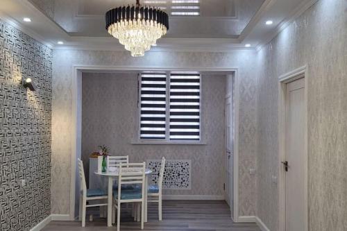 タシュケントにあるCozy New Apartment in a Quite Neighborhoodのテーブルとシャンデリアのあるダイニングルーム