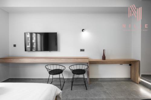 two chairs sitting next to a table with a tv on a wall at Pantheon, Nilie Hospitality MGMT in Thessaloniki