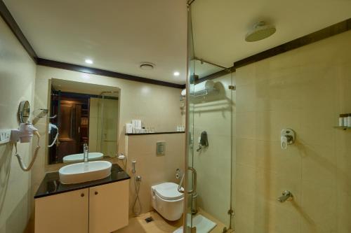 a bathroom with a toilet and a sink and a shower at The Raviz Kadavu, Kozhikode in Kozhikode