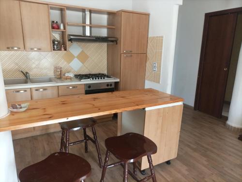 una cucina con bancone in legno e 2 sgabelli di Appartamento in centro a Vibo Valentia