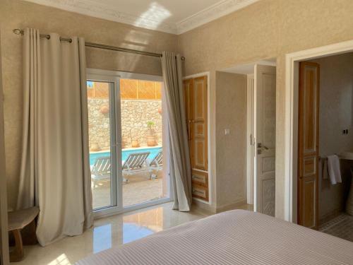 een slaapkamer met een bed en een glazen schuifdeur bij Villa mirleft DEA in Mirleft
