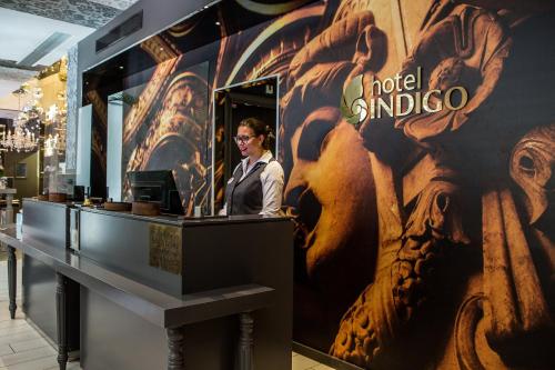 a woman standing at a counter in a store at Hotel Indigo Paris - Opera, an IHG Hotel in Paris