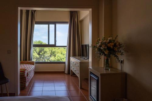 a bedroom with a vase of flowers on a dresser with a window at Hotel Alcossebre in Alcossebre