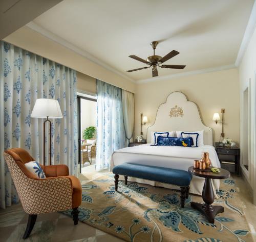 a bedroom with a bed and a chair at Taj Usha Kiran Palace, Gwalior in Gwalior