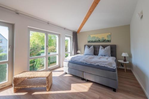 Schlafzimmer mit einem großen Bett und Fenstern in der Unterkunft Ferienhaus an der alten Gärtnerei - Rosmarin in Heiligendamm