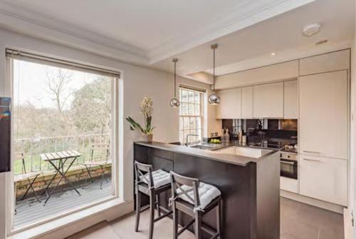 cocina con barra con sillas y ventana grande en The Harrington - Knightsbridge - 18 Rutland Gate, en Londres