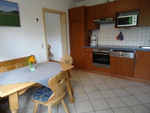 Il comprend une petite cuisine avec une table et des chaises en bois. dans l'établissement Hinterbauernhof Fewo Pferdeglück, à Stegen