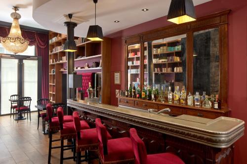 un bar dans un restaurant avec des chaises rouges dans l'établissement Hotel Les Théâtres, à Paris