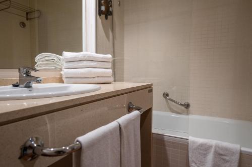 a bathroom with a sink and a tub and towels at Hotel Alcossebre in Alcossebre