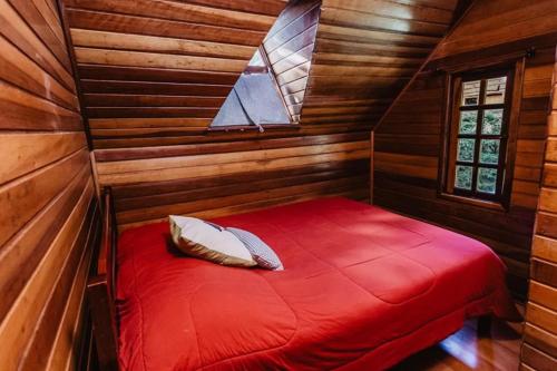 Cette petite chambre comprend un lit rouge dans une cabine. dans l'établissement Chalé São Bernardo - banheira de hidromassagem privativa, à Paiol Grande