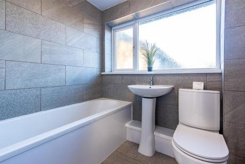 a bathroom with a toilet and a sink and a bath tub at Redcroft Green - Modern 3 bedroom house in Kenton