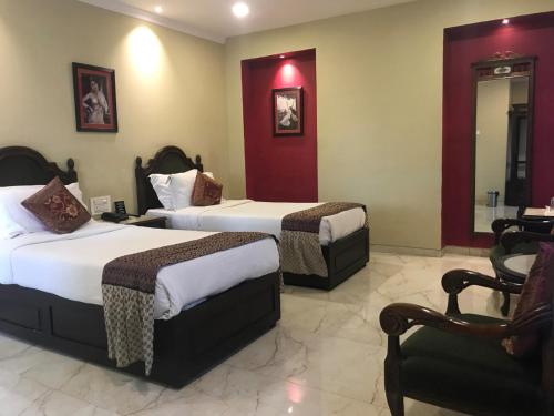 una habitación de hotel con 2 camas y una silla en Pratap Palace, en Chittorgarh