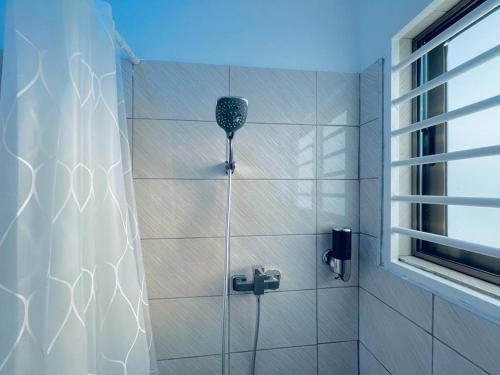y baño con ducha y cortina de ducha. en Rakka Guest House, en Adentan