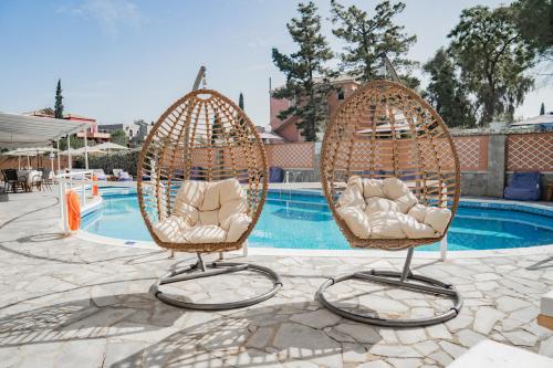 two wicker chairs sitting next to a swimming pool at Maltezos Hotel in Gouvia