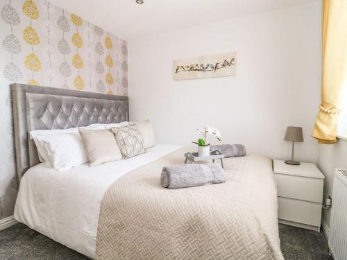 um quarto com uma cama com lençóis brancos e almofadas em The Whyte Retreat em Hornsea
