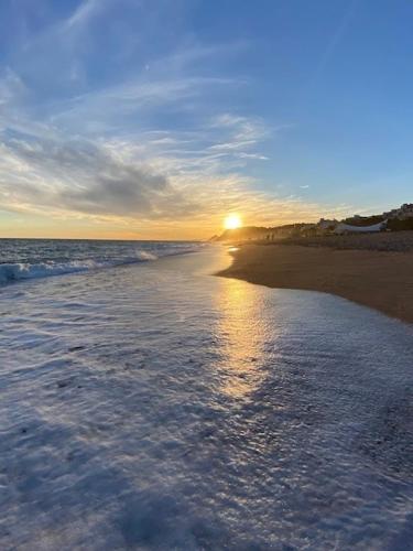a sunset on a beach with the ocean at The Hollidays Apartment in Calella
