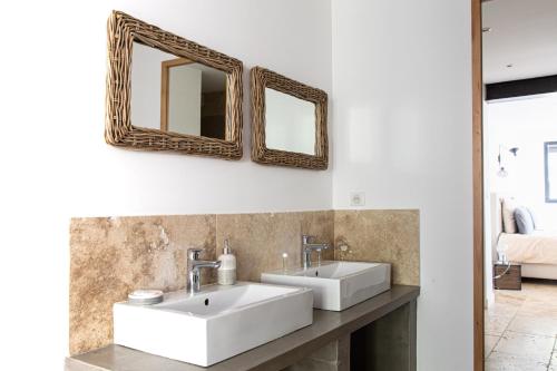 a bathroom with two sinks and mirrors on the wall at Mas lou Félibrige in Venelles
