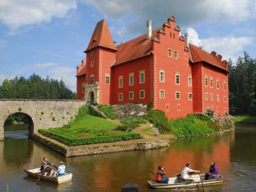 people in boats in the water in front of a castle at Hotel Concertino Zlatá Husa in Jindrichuv Hradec