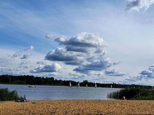 a beach with sailboats on a lake with a cloudy sky at Apartament Nad Zalewem Zegrzyńskim in Serock