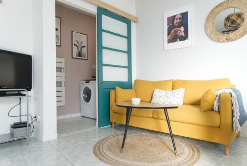 un salon avec un canapé jaune et une table dans l'établissement Le Farniente, belle maison près du port, à La Rochelle