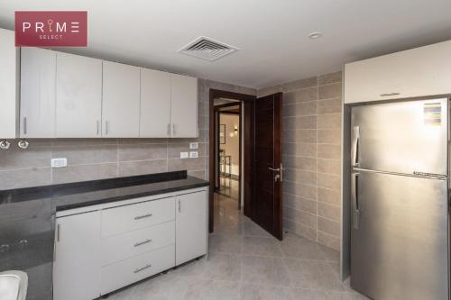 a kitchen with white cabinets and a stainless steel refrigerator at Prime Select New Giza in Giza