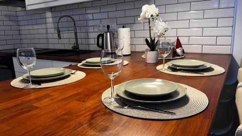 a wooden table with plates and wine glasses on it at APARTMENT KRISTINA in Dunajská Streda