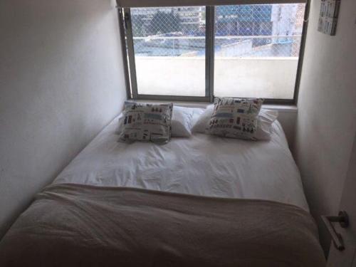 Kennedy Premium Apartments Colorado في سانتياغو: سرير مع وسادتين في غرفة مع نافذة