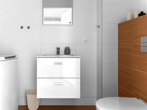 a white bathroom with a sink and a toilet at VacationClub - Apartamenty Piano Apartament 3 in Świeradów-Zdrój