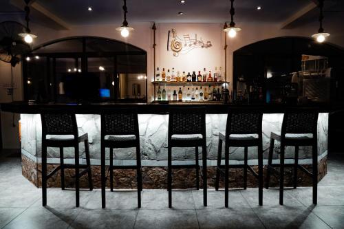 a bar with four chairs in a room at Maltezos Hotel in Gouvia