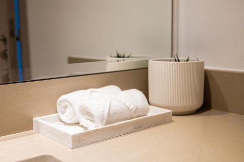 uma pilha de toalhas sentadas num balcão na casa de banho em One Bedroom Hosted By Voyage em Abu Dhabi