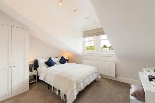 a white bedroom with a bed and a window at Lovely Central Apartment with Park Views in London