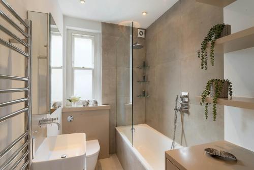 a bathroom with a tub and a toilet and a sink at Lovely Central Apartment with Park Views in London