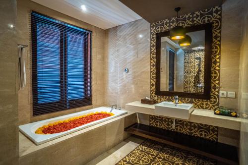 een badkamer met een bad, een wastafel en een spiegel bij djabu Echo Beach Hotel in Canggu