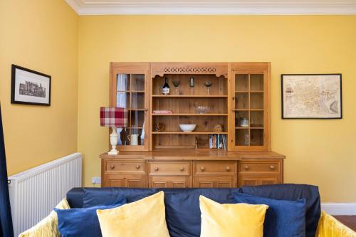 a living room with a cabinet and a blue couch at Edinburgh Holyrood Park Views Apartment in Edinburgh