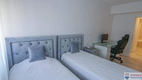 2 camas en una habitación con escritorio y silla en Poseidon Residence, en Bucarest
