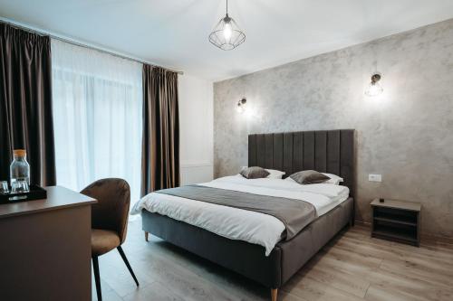 a bedroom with a bed and a desk and a chair at NOR Villa in Ciungetu