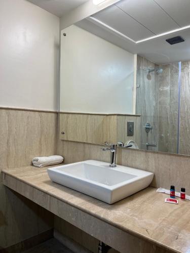 a bathroom counter with a sink and a mirror at Karon Hotels - Lajpat Nagar in New Delhi