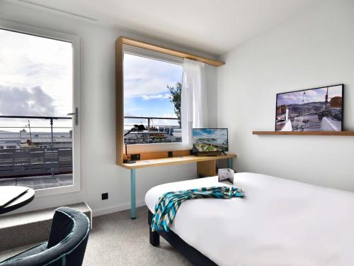 ブレストにあるibis Styles Brest Centre Portのベッド2台、デスク、窓が備わる客室です。