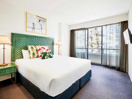 a bedroom with a large bed and a large window at The Sebel Sydney Manly Beach in Sydney