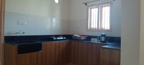 a kitchen with a sink and wooden cabinets at The Heritage Serviced Apartments Mysuru in Mandya