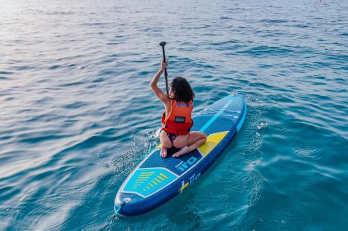 a woman sitting on a paddle board in the water at Blue And Blue City in Ugento