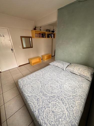 Schlafzimmer mit einem Bett mit blauer Decke in der Unterkunft Quarto próximo à praia in Balneário Camboriú