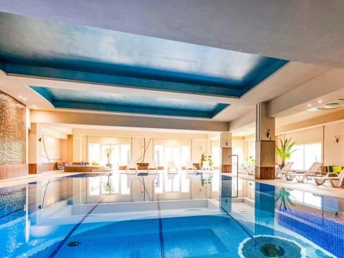 拉茨瓦維採的住宿－拉茨瓦維採多斯洛尼采美居酒店、會議中心及水療中心，一座拥有蓝色天花板的大型游泳池