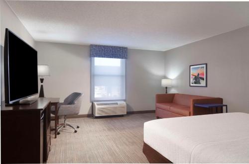 a hotel room with a bed a desk and a television at Hampton Inn Evansville in Evansville