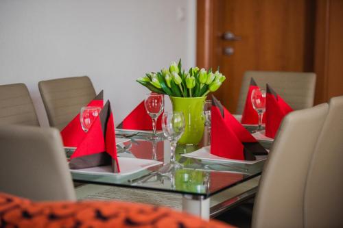 a glass table with red napkins and a vase of flowers at Apartments Villa Monique in Rogoznica
