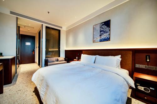 a bedroom with a large white bed and a chair at Jingmao Alley Hotel - Beijing Wangfujing Dongsi Subway Station Branch in Beijing