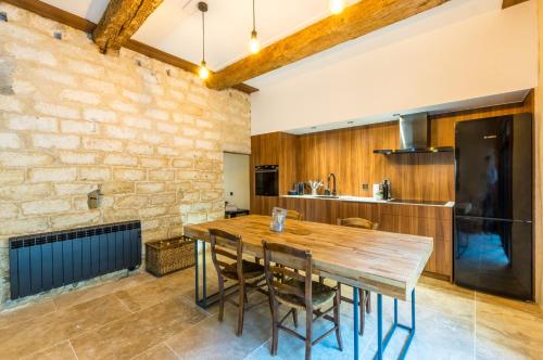 une cuisine avec une table en bois et un mur en briques dans l'établissement Atelier Ecusson - Premiere conciergerie, à Montpellier