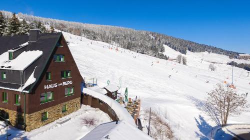 ein Gebäude auf einem schneebedeckten Berg mit einer Skipiste in der Unterkunft Haus am Berg - Pension direkt am Skihang in Kurort Oberwiesenthal